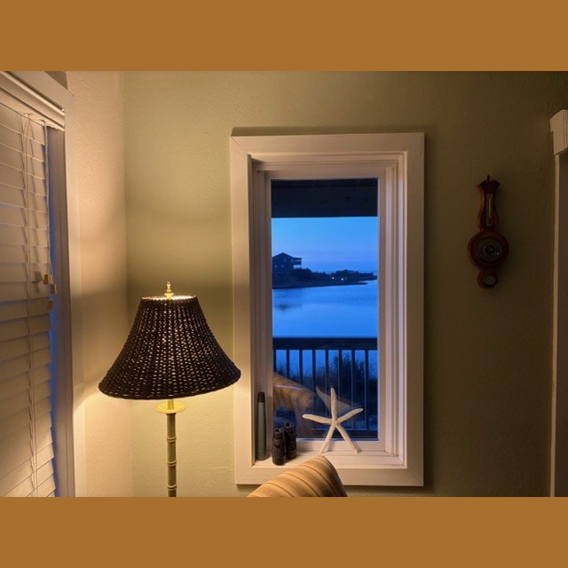 Lamp, binoculars, and starfish decor by a window with a view of water and buildings at dusk.