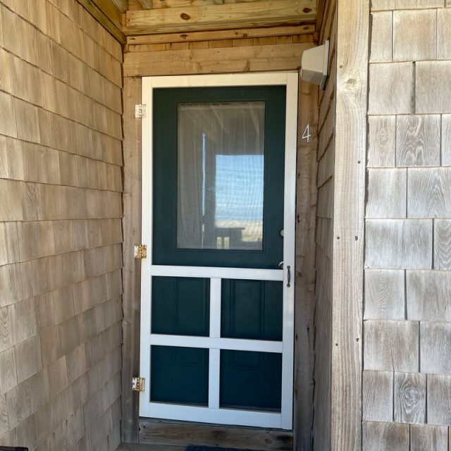 Screen door with a green lower panel and white trim on a shingled exterior wall, marked with the number 4.