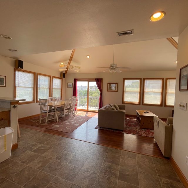 Open living and dining area with tile flooring, couches, dining table, large windows, and a glass door to a balcony.