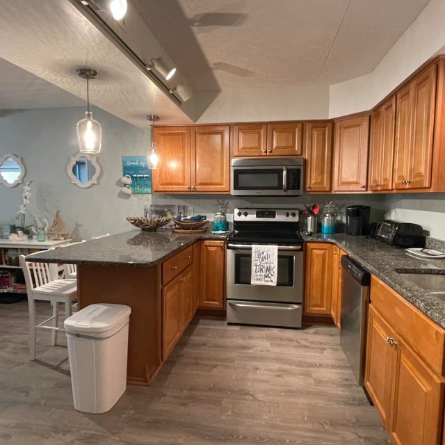 Modern kitchen with wooden cabinets, stainless steel appliances, granite countertops, and a small dining area.