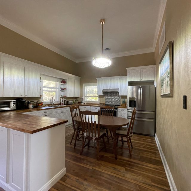 Kitchen with wooden cabinets, dining table with four chairs, stainless steel appliances, and a hanging light fixture.