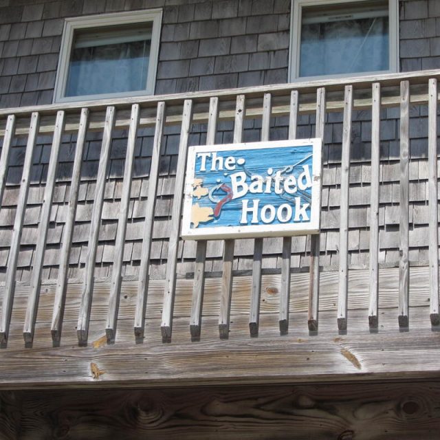 A wooden balcony with a sign that reads “The Baited Hook” featuring a fish and water graphic.